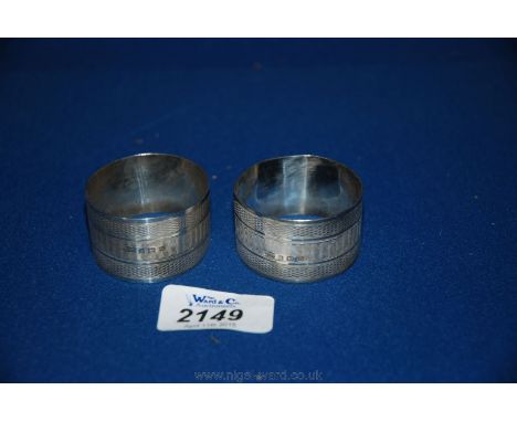 A pair of matching Silver Napkin Rings with engine turned decoration and engraved, Nos. 6 and 3
