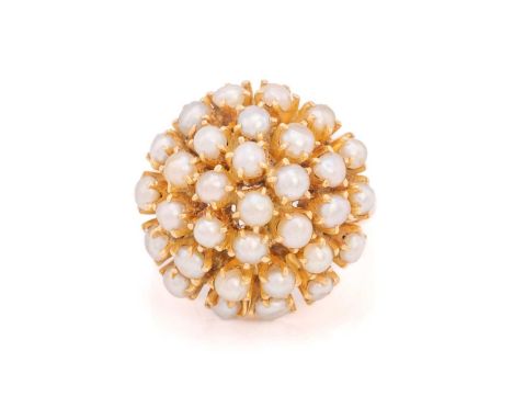 A seed pearl cocktail bombé ring, comprising a domed cluster of seed pearls in open back claw settings, with fleur-de-lis sho