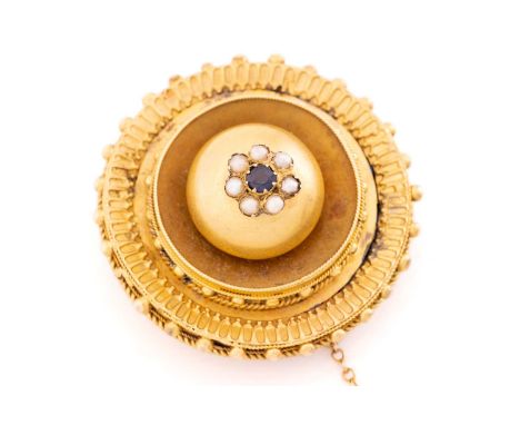 A Victorian mourning brooch in Etruscan Revival design, of domed circular form, centred with a daisy head cluster of garnet-t
