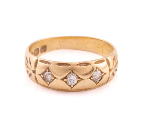 A Victorian 18 carat gold and three stone diamond ring, the round Old European cut diamonds claw set to an engraved tapering 