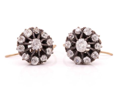 A pair of diamond cluster earrings, each comprising an old-cut diamond in carved claws at the centre, mount surrounded by ten