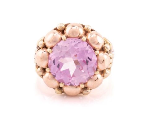 A synthetic pink sapphire dress ring, consisting of a circular-cut synthetic pink sapphire of 12.1 x 12.1 x 7.4 mm, claw set 