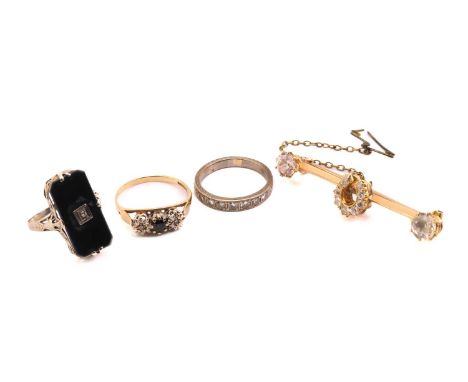 Three gem-set rings and a horseshoe bar brooch; to include an onyx panel ring with a diamond highlight, with embellished unde