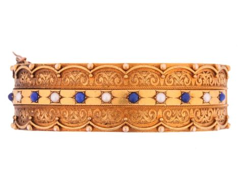 A Victorian hinged bangle set with lapis lazuli and pearls, half of the bracelet comprises an intricately engraved openwork b
