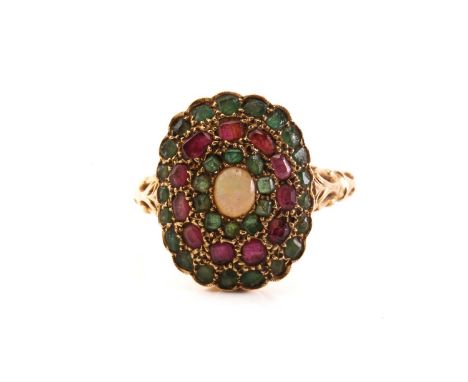 A yellow metal, ruby, emerald, and opal dress ring, centred with an oval cabochon opal, with flush-set circles of emeralds an