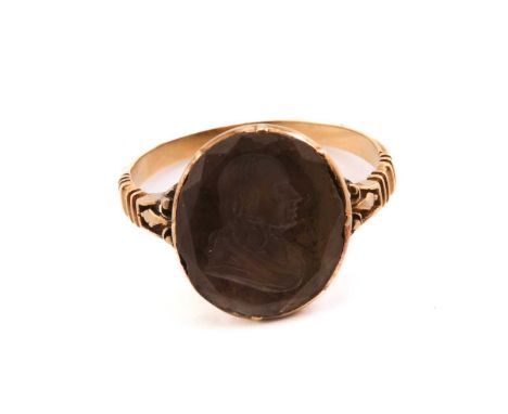 A George III intaglio ring, featuring an oval faceted quartz panel, depicting a profile of a gentleman facing right, set in a