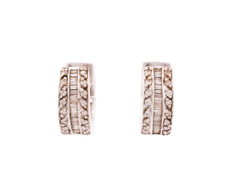 A pair of diamond set huggy hoop earrings, formed from channel set baguette cut diamonds flank in parallel by claw set round 