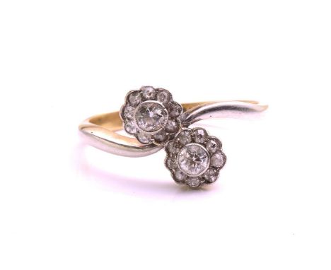 A diamond Toi et Moi crossover ring, scintillating with two flowerhead clusters composed of two old-European cut diamonds sur