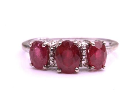 A ruby and white metal three-stone ring, four claw set with three oval mixed cut rubies, the centre stone approximately 7mm b