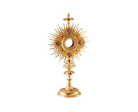 A gilt metal Monstrance, in the Gothic revival style, the glazed aperture surrounded with paste stones and four enamel plaque