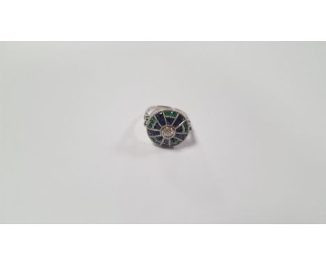 AN UNUSUAL PLATINUM TARGET-STYLE RING SET WITH CENTRAL DIAMOND, CALIBRE-CUT SAPPHIRES AND EMERALDS AND FURTHER DIAMONDS TO TH