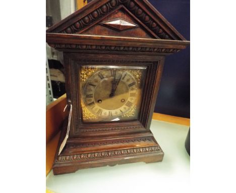 A 19thC oak cased bracket clock of architectural form with silvered chapter ring and Roman numerals flanked by brass foliate 