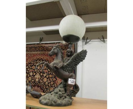 A table lamp in the form of a cherub riding Pegasus with crackle glass globe shade.