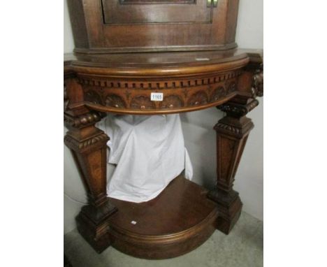 A mahogany corner shelf with carved lion head supports,.