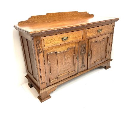 Edwardian oak sideboard, raised and shaped back, two short drawers above two cupboard doors enclosing fitted interior, shaped