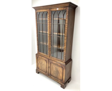 20th century mahogany bookcase, projecting cornice, two doors enclosing three adjustable shelves above two cupboards, bracket