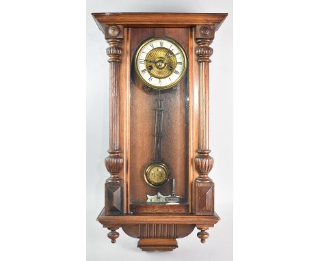 An Early 20th Century Oak Cased Vienna Style Wall Clock, with pendulum and Key, the Brass Face with Enamel Chapter Ring Havin