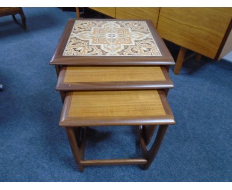 A nest of three mid-20th century teak G-Plan tables one with tiled inset panel.