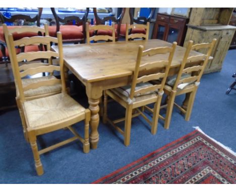 A pine farmhouse kitchen table together with a set of six rush seated ladder back chairs.