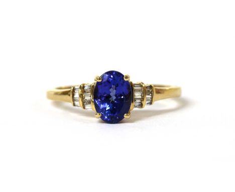 An 18ct gold tanzanite and diamond ring, with an oval mixed cut tanzanite, approximately 8 x 6mm, claw set, with two rows of 