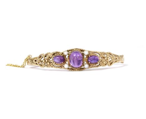 A 9ct gold amethyst and split pearl bangle, with three oval cabochon amethysts claw set to the tapered top half, with pairs o