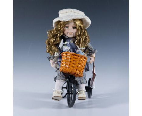 This limited-edition doll is designed with long curly hair, dressed for outdoor play, wearing her hat and riding her tricycle