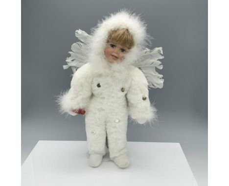 Darling figure of a child in a one piece fluffy suit decorated with snowflakes and wings while holding a red bird. Metal stan