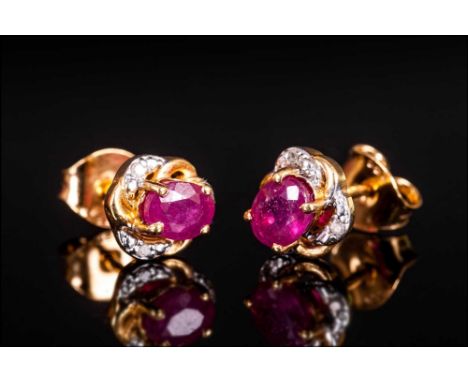 Pair of Ruby Stud Earrings with diamond accents, the oval cut rubies, of good colour, set in a frame of alternating 14ct gold