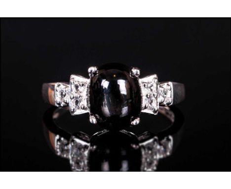 Black Star Diopside and White Topaz Ring, an oval cut cabochon of 2.75cts of black star diopside, displaying a four-pointed s