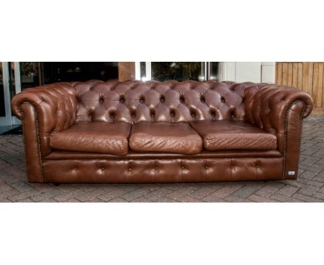 Brown Leather Three Seater Button Back Chesterfield Settee with three loose seat covers terminating on castor feet. 82'' in w