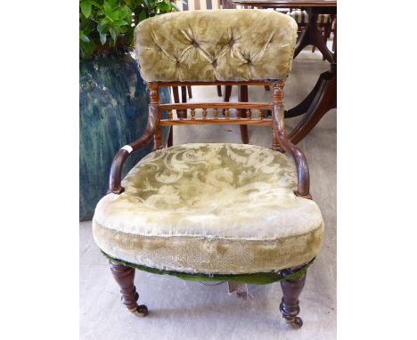 An early 20thC mahogany framed nursing chair with a low, curved crest, a galleried horizontal splat and open, swept arms, par