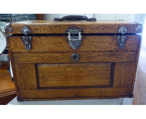 An early/mid 20thC light oak tool chest with straight sides and a hinged lid, the fall front enclosing an arrangement of seve