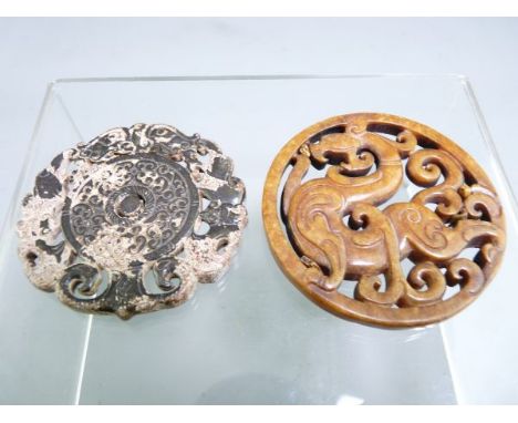 TWO CHINESE CARVED JADE ROUNDELS, one showing a mythical beast, 6.75cms diameter, the other having a swirl decorated centre a
