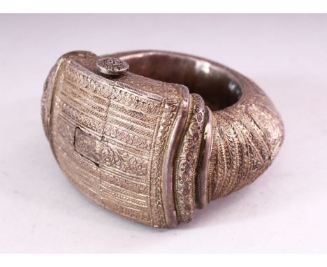 A PERSIAN WHITE METAL SLAVE BANGLE, with engraved and embossed decoration, 12cm wide.