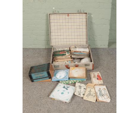 A suitcase with contents of vintage sewing patterns, Airlyne rugmaker, linens, etc.  