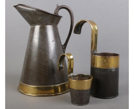 A brass bound toleware brass banded measuring jug and two measuring cups, just stamped â€˜ARMY &amp; NAVY C.S.L. MAKERSâ€™. S