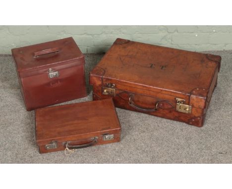 Three vintage leather suitcases of varying sizes with two monogramed to fronts.  