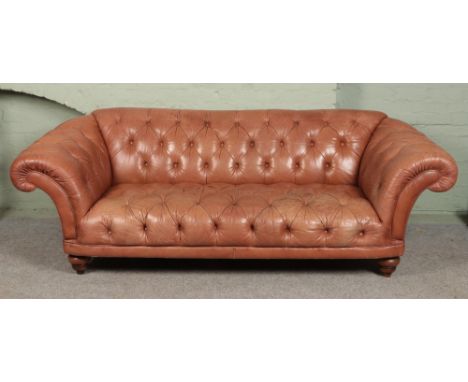 A brown leather chesterfield type sofa raised on bun feet.Length 250cm approx  Some discolouration to leather on right side o