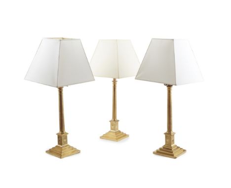 THREE GILT BRASS CANDLESTICKS  19TH CENTURY   the plain columns on square plinths engraved with starbursts, ending on stepped