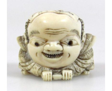 A late Meiji period Japanese ivory netsuke, formed as a grotesque figure head on shaped foot, unsigned, 3cm wide.