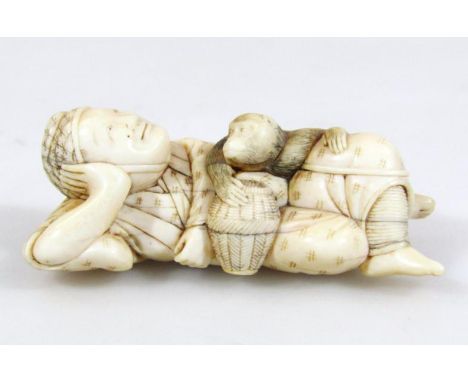 A Japanese Meiji period netsuke, formed as a reclining gentleman in flowing robes aside monkey, double drill holes beneath, u