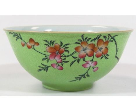 A Chinese porcelain bowl, the circular green glazed body etched with stylised scrolls and hand painted with flowers on a circ