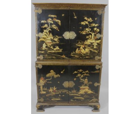 A two sectional English oriental design lacquered blanket cupboard, the upper section with an overhanging top raised above a 