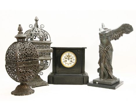 A Victorian black slate mantel clock with visible escapement, 2 metal candle lamps and a winged resin figure (after figure in