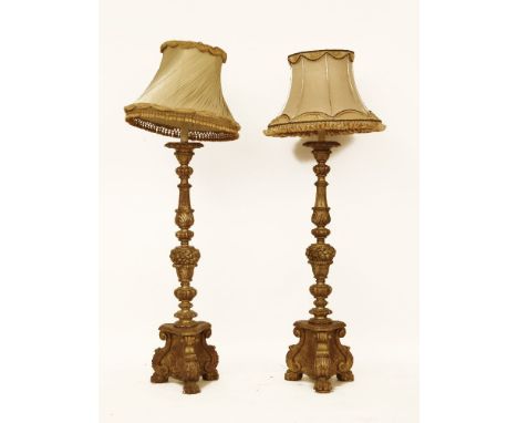 A pair of gilt wood lamp standards, with trefoil bases and different shades