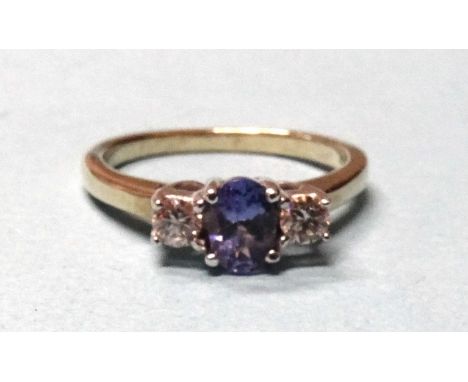 A 9ct gold ring set an oval Tanzanite between two brilliant-cut diamonds, in 9ct gold mount. 