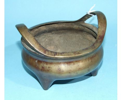 An Oriental bronze censor, the rim with raised handles, on three feet, mark beneath, 14cm diameter. 