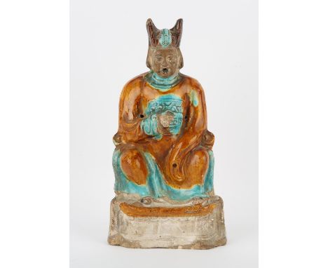 A glazed ceramic, Fahua [or other] figure of a seated scholar; decorated with ochre, turquoise and aubergine glazes; the reve