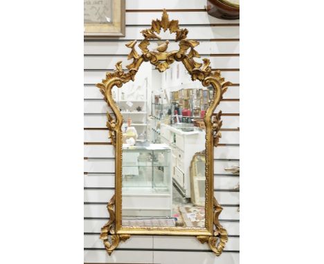 LOT WITHDRAWN
Giltwood framed mirror in the rococo manner, the moulded frame surmounted by a bird within foliage, 103cm x 56c