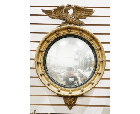 Giltwood-effect wall mirror in the Regency manner, the circular convex mirror surmounted by an eagle and with ball frieze, 68